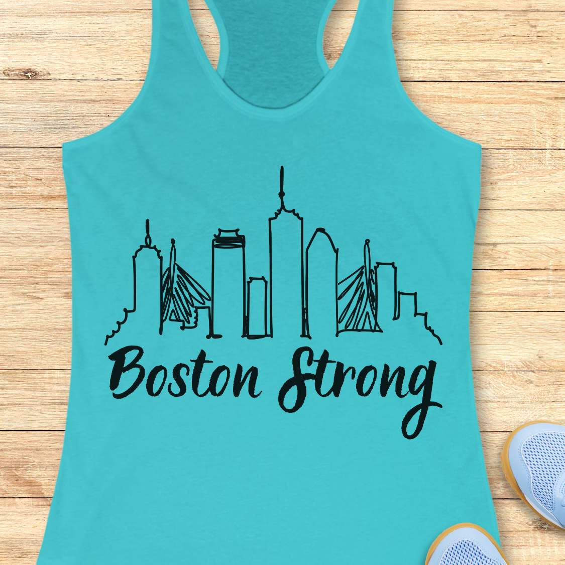Turquoise tank top with black 'Boston Strong' skyline design on a wooden surface