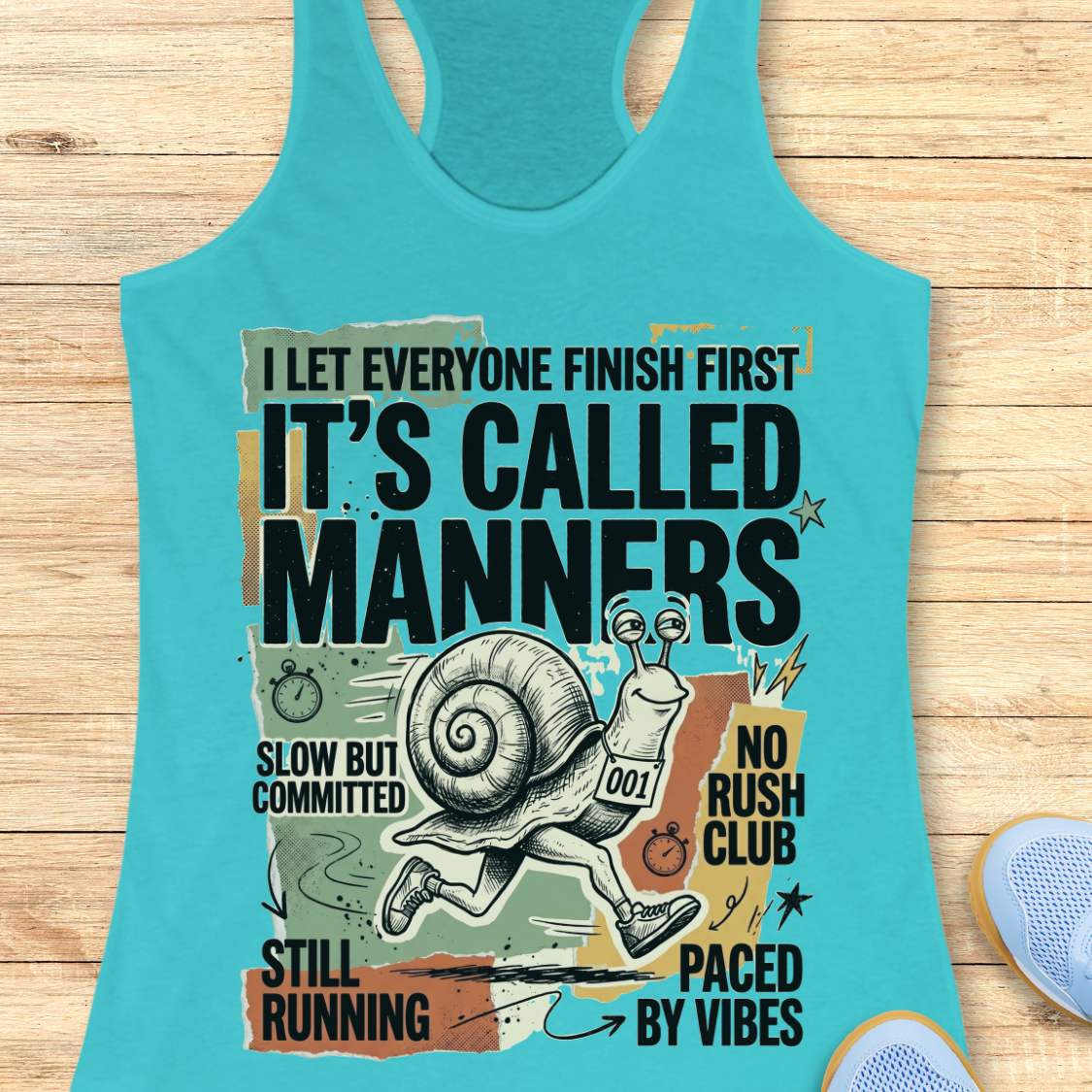 Turquoise tank top with a graphic design featuring a snail and text on a wooden surface
