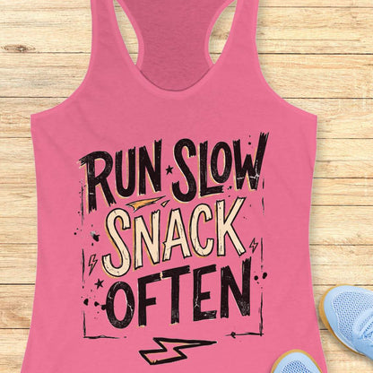 Pink tank top with 'RUN SLOW SNACK OFTEN' text on a wooden surface