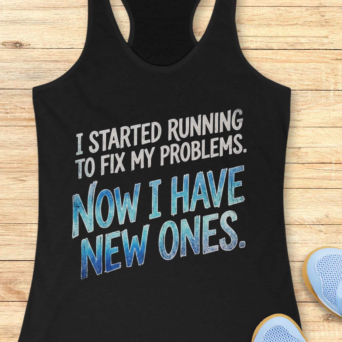 Black tank top with humorous text 'I started running to fix my problems. Now I have new ones.' on a wooden surface