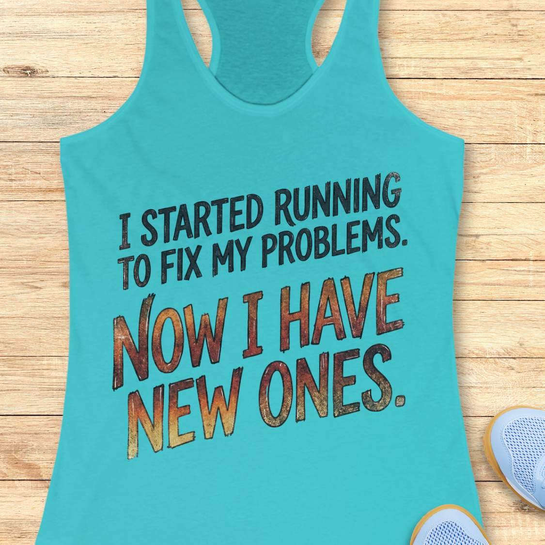 Turquoise tank top with humorous text 'I started running to fix my problems. Now I have new ones.' on a wooden surface