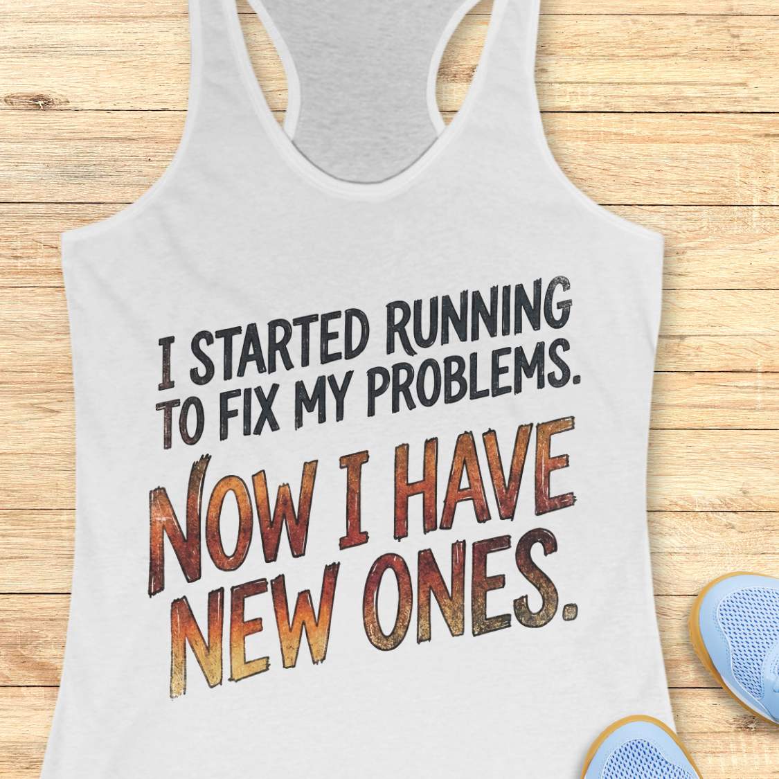 white tank top with humorous text 'I started running to fix my problems. Now I have new ones.' on a wooden surface