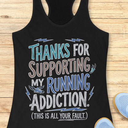 Black tank top with humorous text 'thanks for supporting my running addiction. (This is all your fault.)' design on a wooden surface