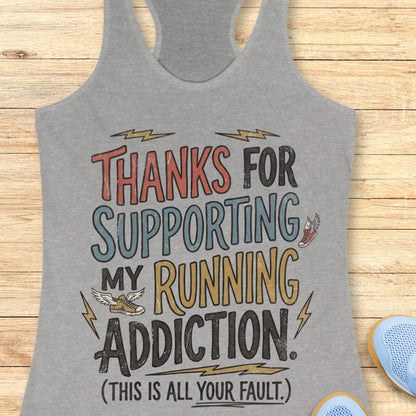 Gray tank top with humorous text 'thanks for supporting my running addiction. (This is all your fault.)'  design on a wooden surface
