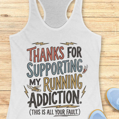 white tank top with colorful text 'thanks for supporting my running addiction. (This is all your fault.)'  on a wooden surface