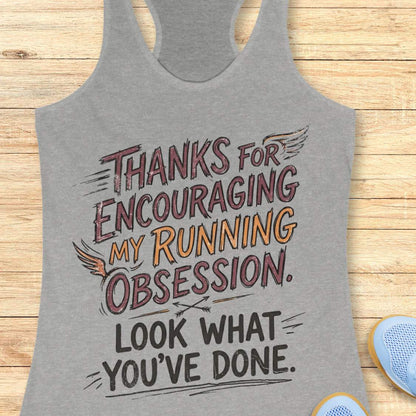 Gray tank top with motivational text 'Thanks for encouraging my running obsession. Look what you've done.' on a wooden surface