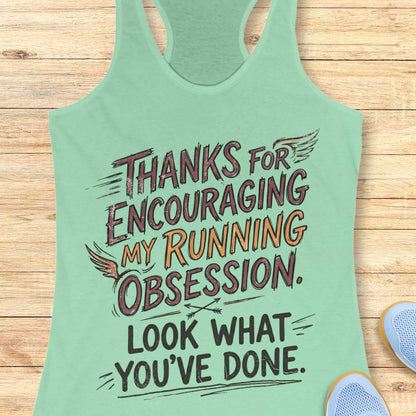 Green tank top with motivational text 'Thanks for encouraging my running obsession. Look what you've done.' on a wooden surface
