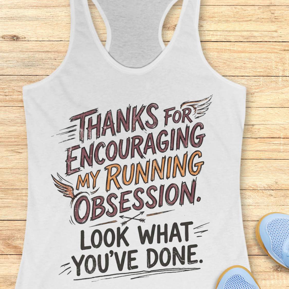 white tank top with motivational text 'Thanks for encouraging my running obsession. Look what you've done.' on a wooden surface