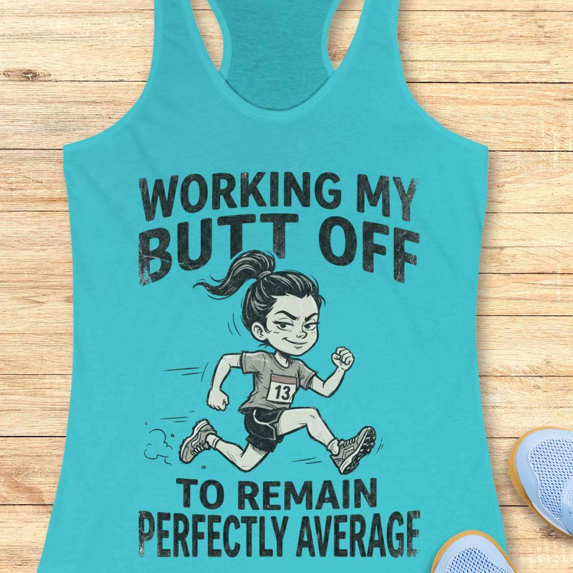 Turquoise tank top with a graphic of a runner and text  'working my butt off to remain perfectly average', on a wooden surface