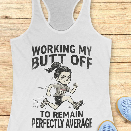 white tank top with a graphic of a runner and text 'working my butt off to remain perfectly average', on a wooden surface