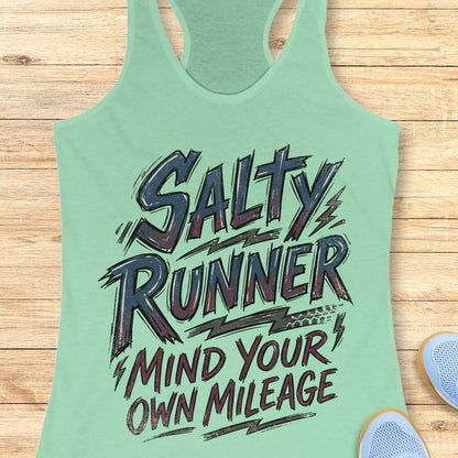 Light green tank top with 'Salty Runner Mind Your Own Mileage' text on a wooden surface.
