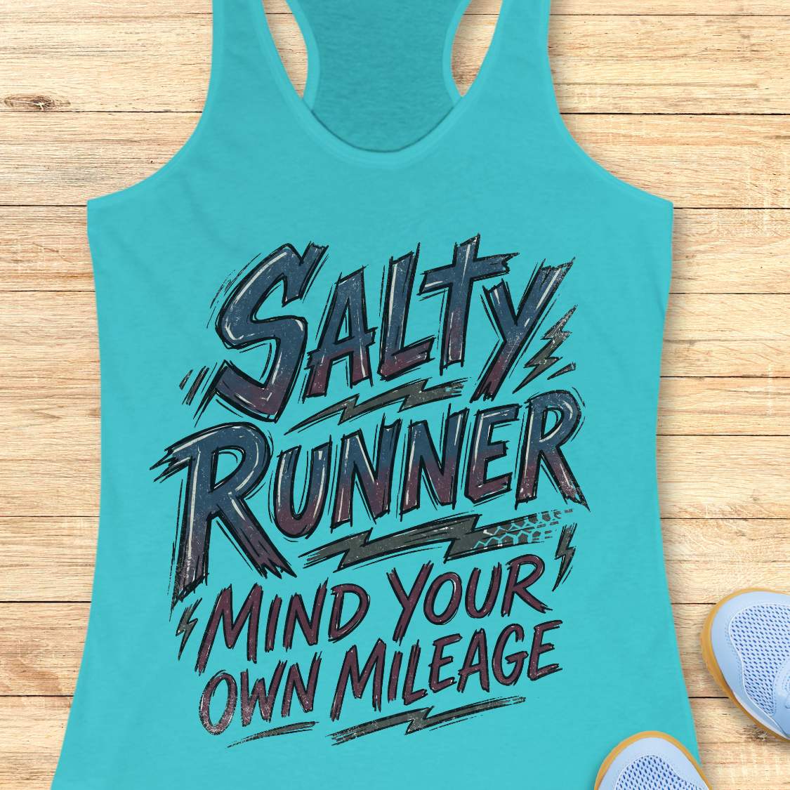 Turquoise tank top with 'Salty Runner Mind Your Own Mileage' text on a wooden surface.