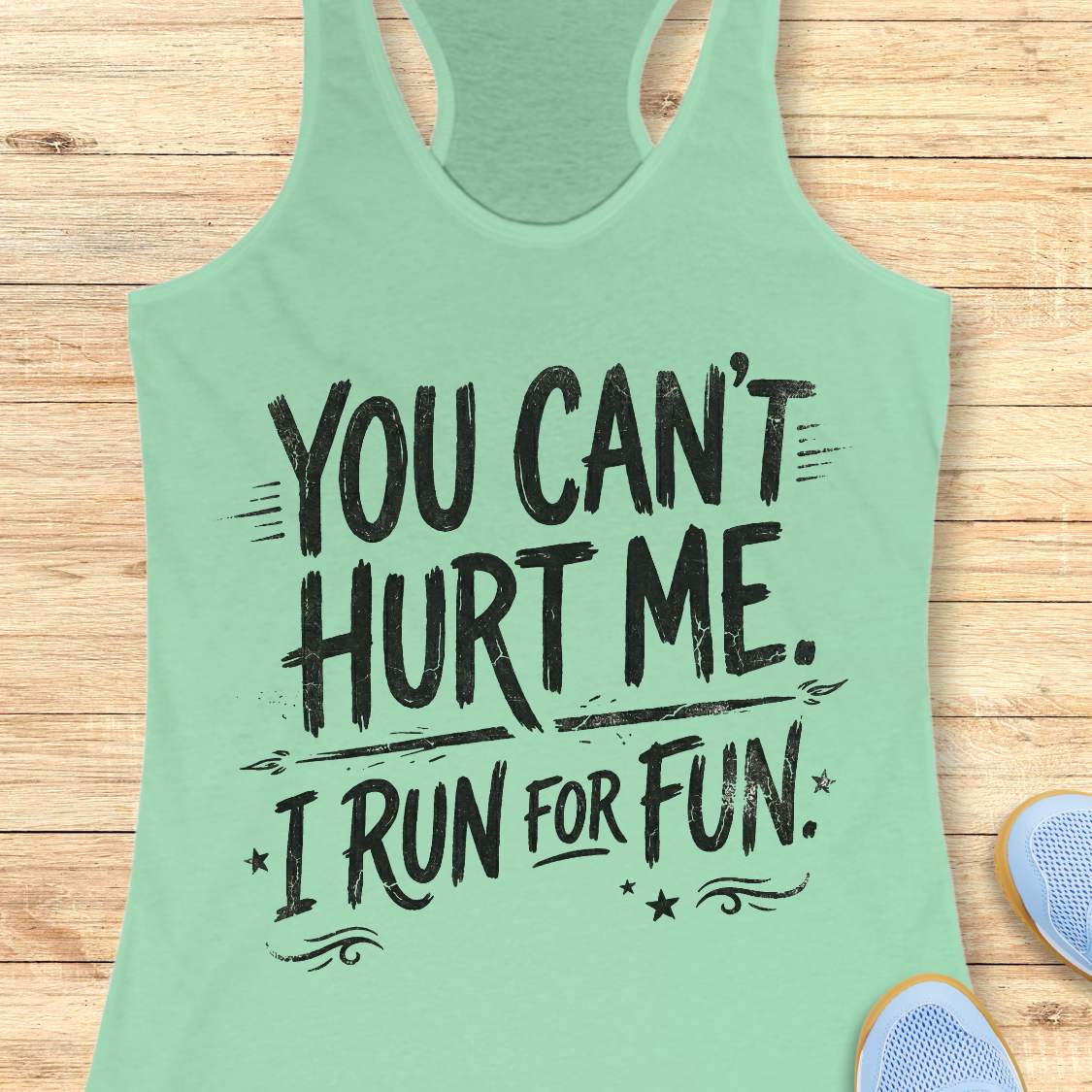 Mint green tank top with text 'You can't hurt me. I run for fun.' on a wooden surface.