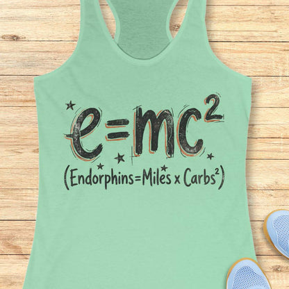 Mint green tank top with a humorous equation printed on it, with text - 'Endorphins = Miles X Carbs square' placed on a wooden surface.
