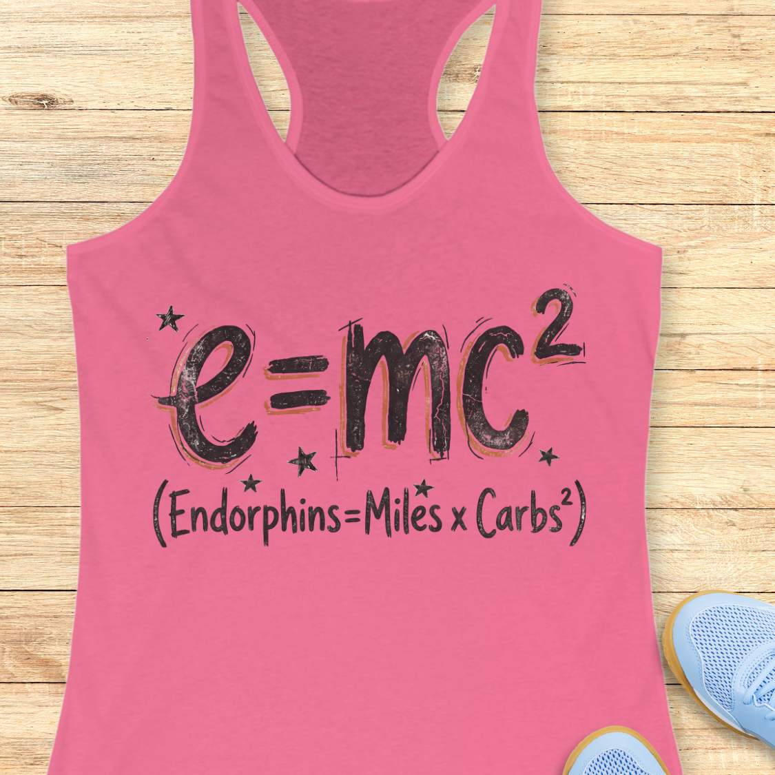 Pink tank top with a humorous equation printed on it, with text - 'Endorphins = Miles X Carbs square' placed on a wooden surface.