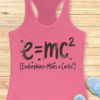 Pink tank top with a humorous equation printed on it, with text - 'Endorphins = Miles X Carbs square' placed on a wooden surface.
