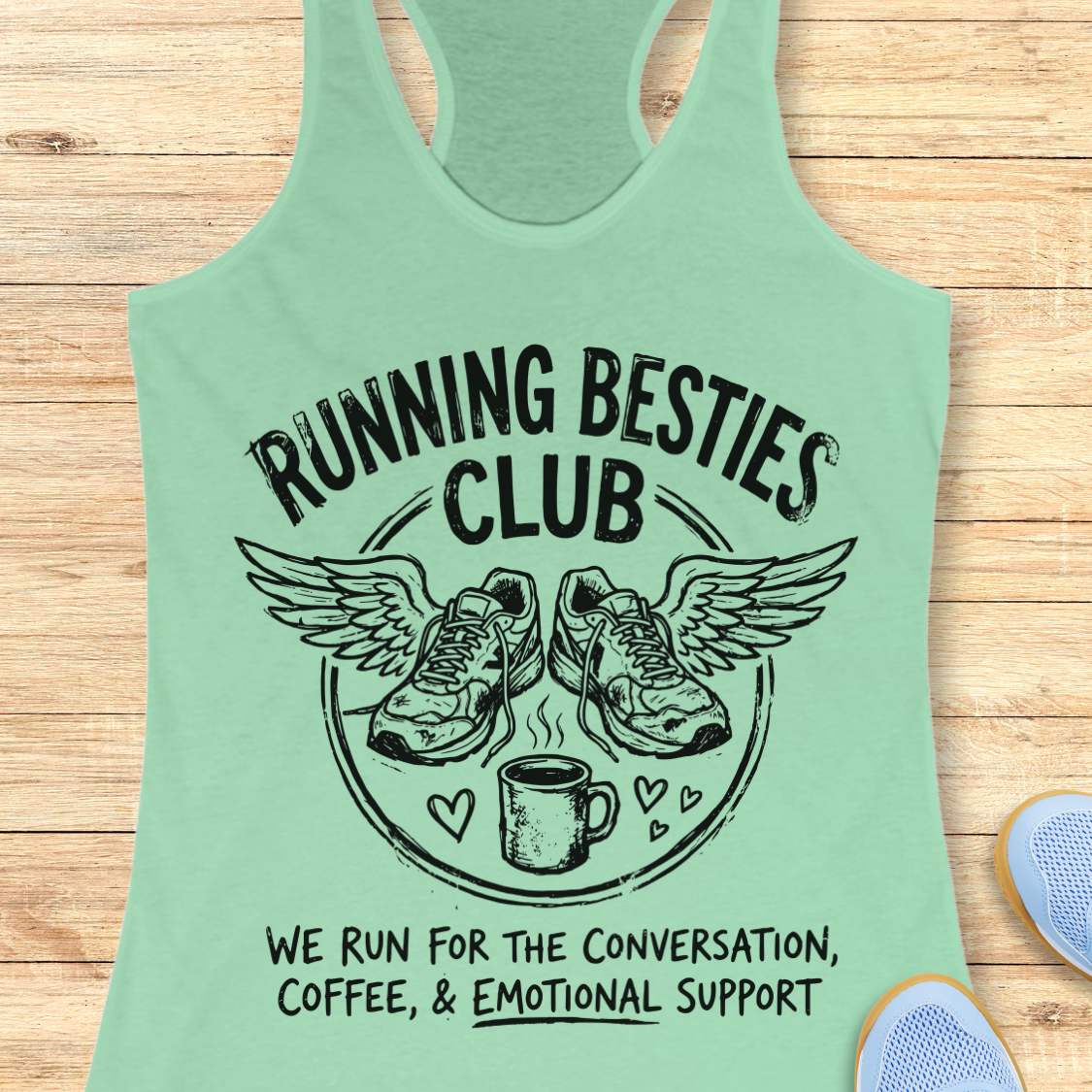 Light green tank top with 'Running Besties Club' design on a wooden surface