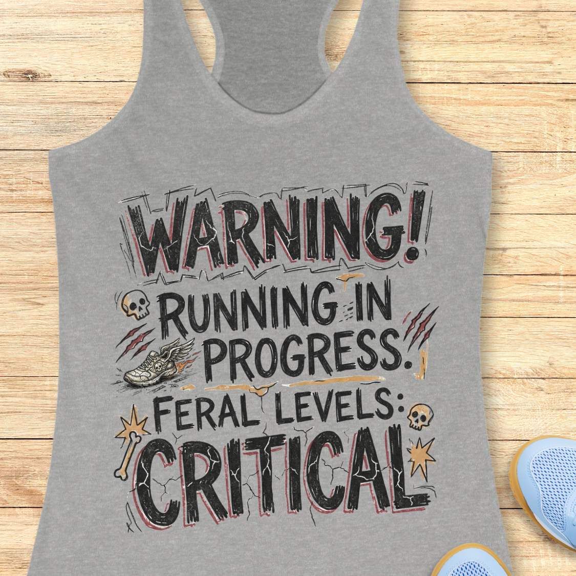 Gray tank top with humorous text 'warning running in progress, feral levels critical' ,design on a wooden surface