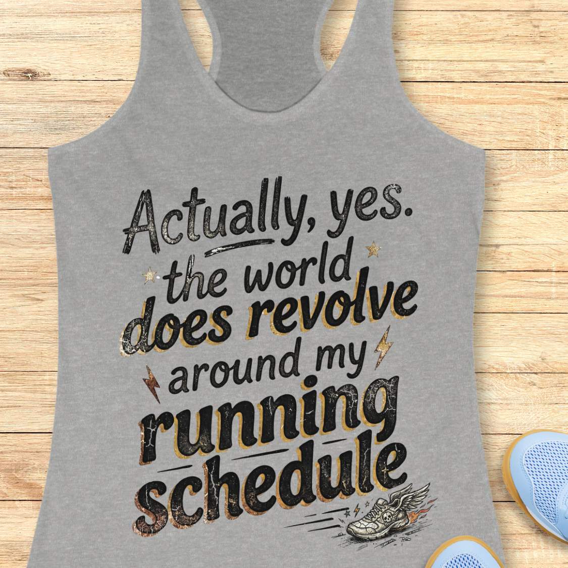 Gray tank top with funny text 'Actually, yes. the world does revolve around my running schedule.',  on a wooden surface
