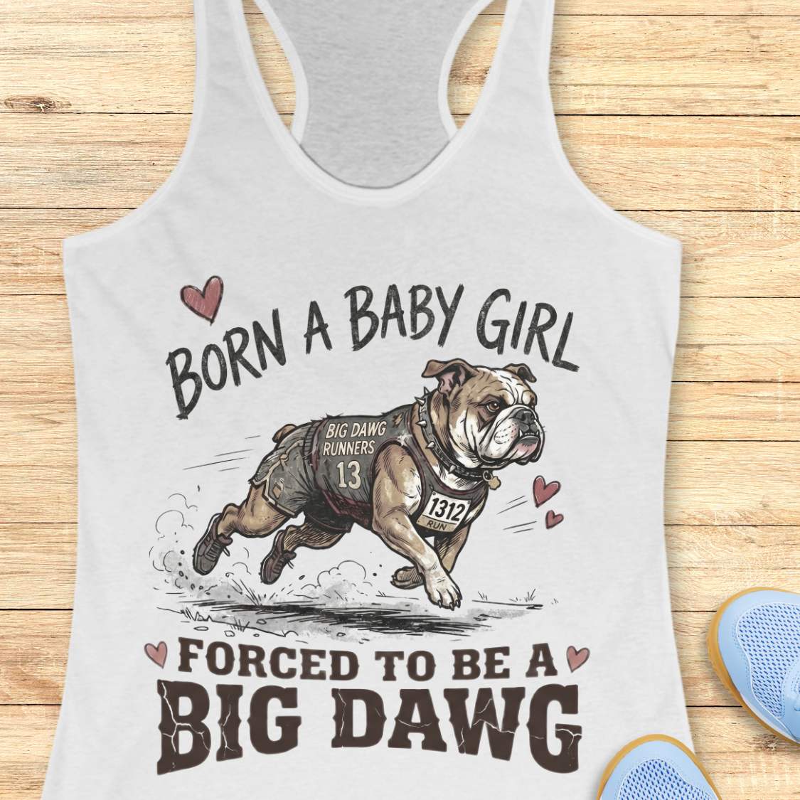 white tank top with bulldog graphic and text 'Born a baby girl forced to be a BIG DAWG', on a wooden surface