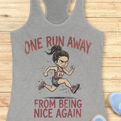 Gray tank top with a graphic of a runner and text 'One Run Away From Being Nice Again' on a wooden surface.
