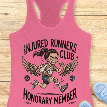 Pink tank top with 'Injured Runners Club Honorary Member' graphic on a wooden surface.