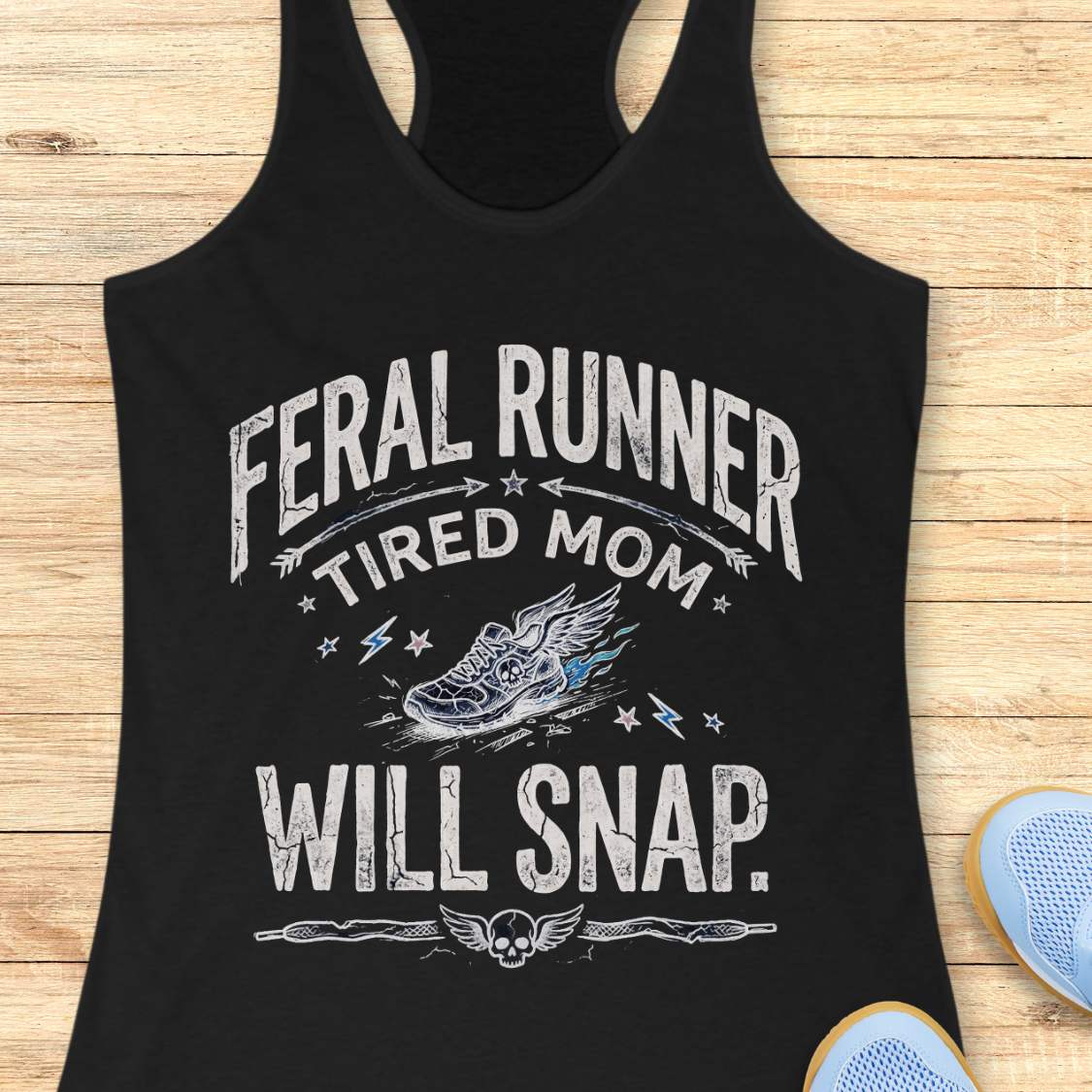 Black tank top with white text 'feral runner, tired mom, will snap.' , and graphic on a wooden surface