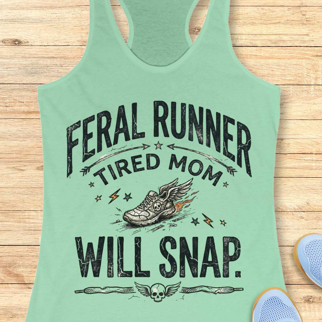 Mint green tank top with text 'feral runner, tired mom, will snap.' , and graphic design on a wooden surface