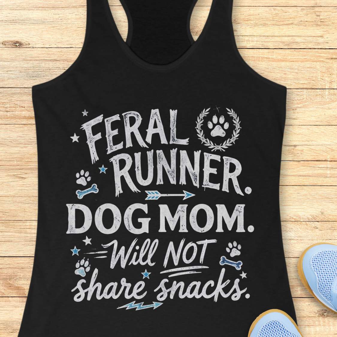 Black tank top with white text 'Feral Runner. Dog Mom. Will Not Share Snacks' on a wooden surface.