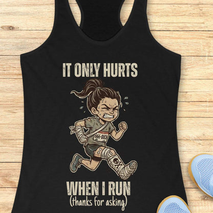 Black tank top with a graphic of a running person and text 'It only hurts when I run (thanks for asking)', on a wooden surface