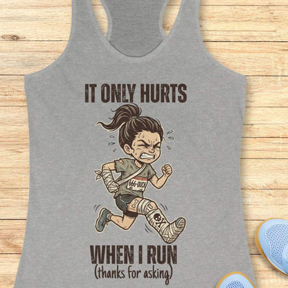 Gray tank top with cartoon character and text 'It only hurts when I run (thanks for asking)', on a wooden surface