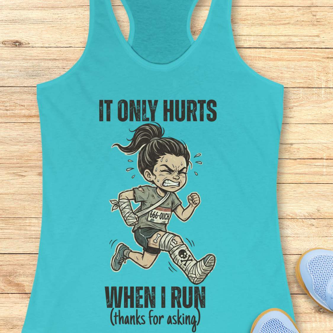 Turquoise tank top with graphic design and text 'It only hurts when I run (thanks for asking)', on a wooden surface