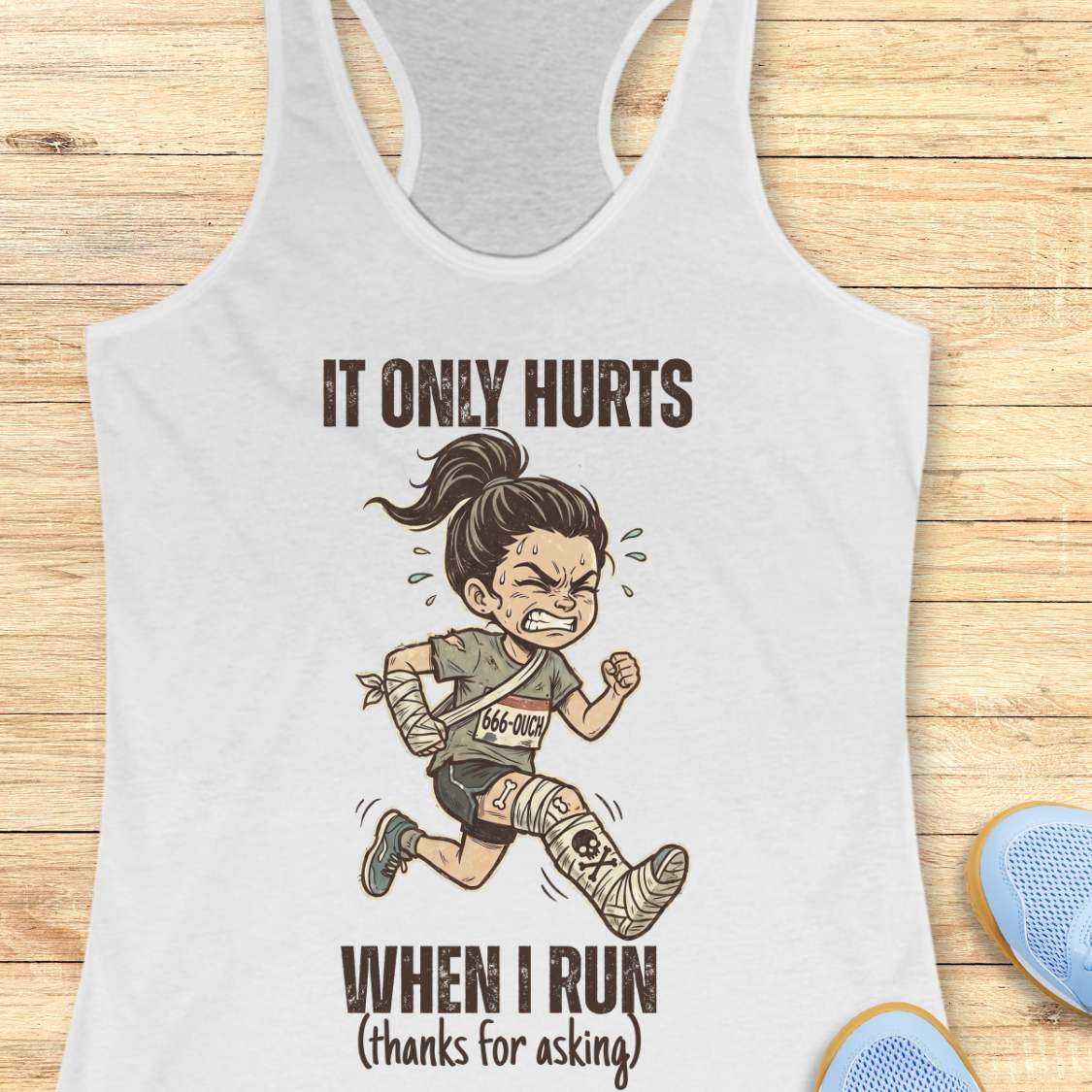 White tank top with graphic of a running person and text 'It only hurts when I run (thanks for asking)', on a wooden surface