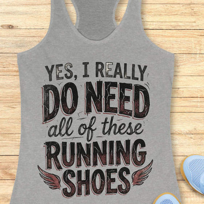 Gray tank top with motivational text ' yes, I really do need all of these running shoes',  on a wooden surface