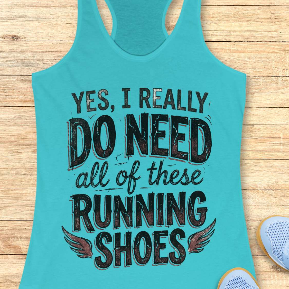 Turquoise tank top with text ' yes, I really do need all of these running shoes', on a wooden surface