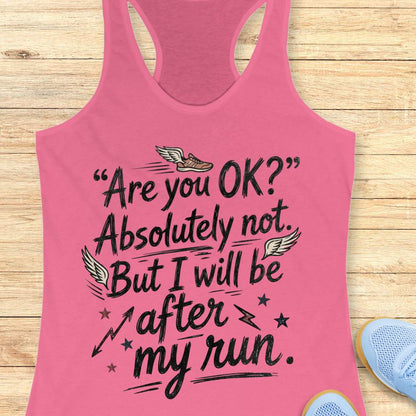 Pink tank top with humorous text 'Are you ok? Absolutely not. But I will be after my run.', design on a wooden surface