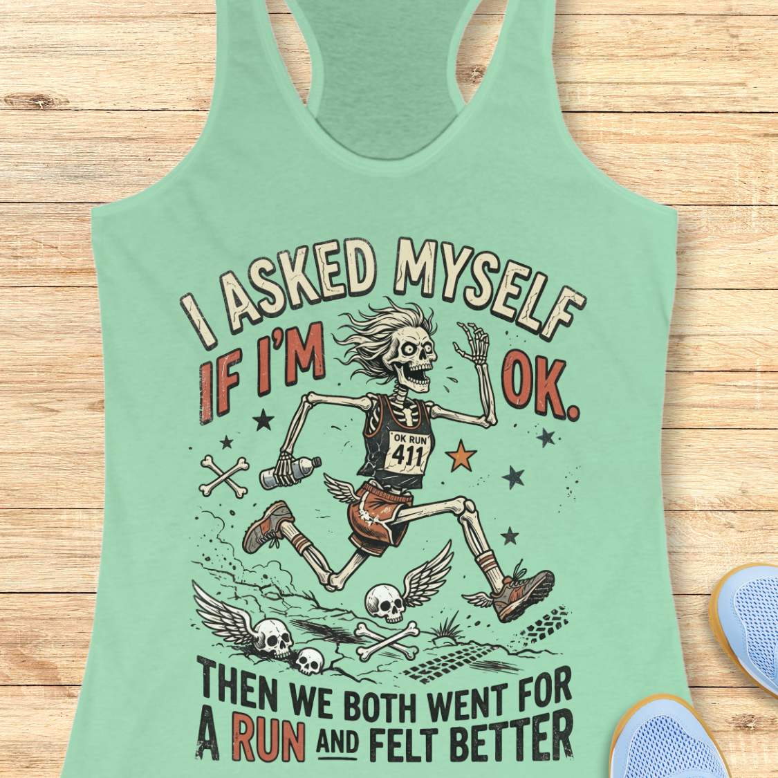 Mint green tank top with skeleton graphic and text 'I asked myself if I'm OK. Then we both went for a run and felt better',  on a wooden surface