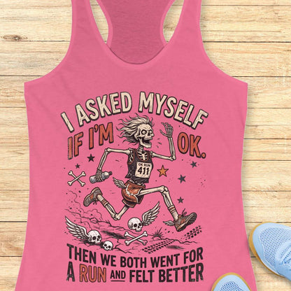 Pink tank top with skeleton design and text 'I asked myself if I'm OK. Then we both went for a run and felt better',  on a wooden surface