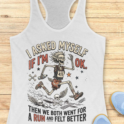 white tank top with skeleton graphic and text 'I asked myself if I'm OK. Then we both went for a run and felt better',  on a wooden surface