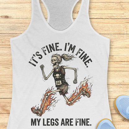white tank top with skeleton design and text 'It's fine. I'm fine. My legs are fine.' on a wooden surface.