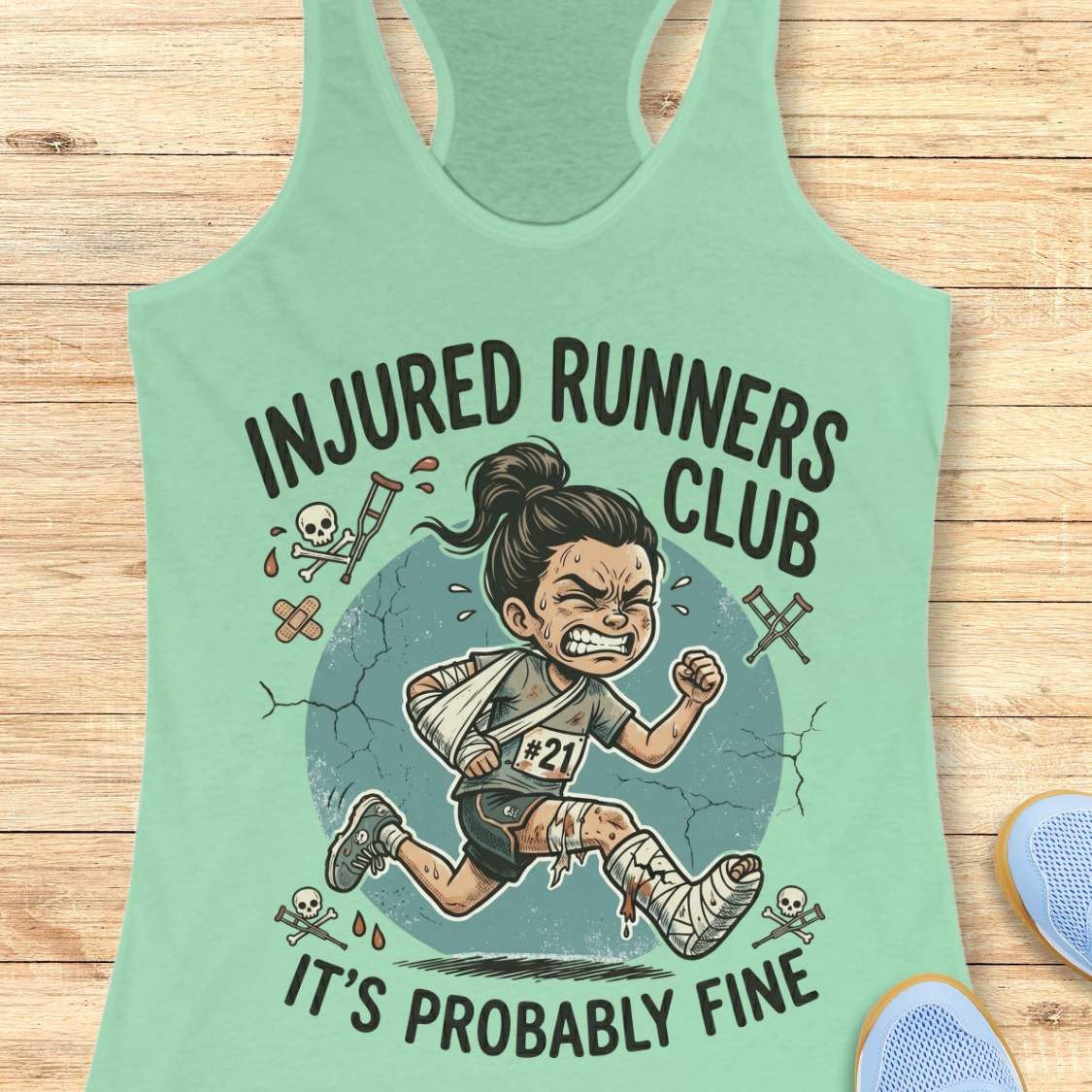 Mint green tank top with 'Injured Runners Club' graphic on a wooden surface