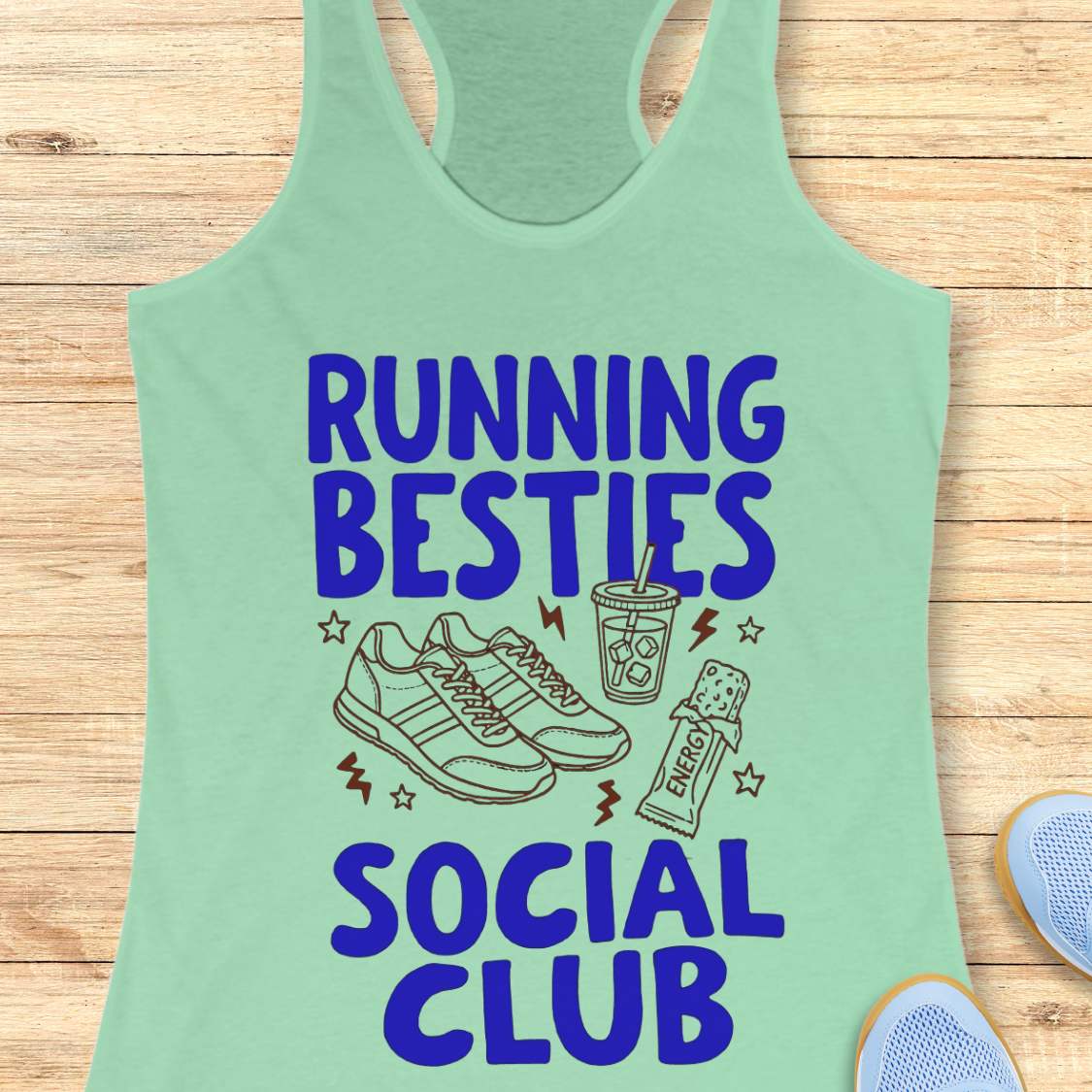Mint green tank top with 'Running Besties Social Club' text and graphics on a wooden surface.