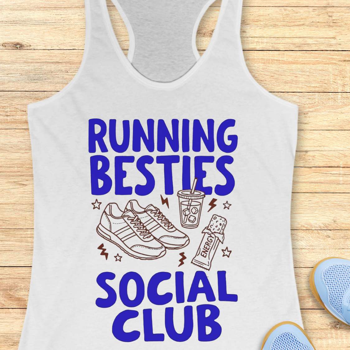 White tank top with 'Running Besties Social Club' text and graphics on a wooden surface.