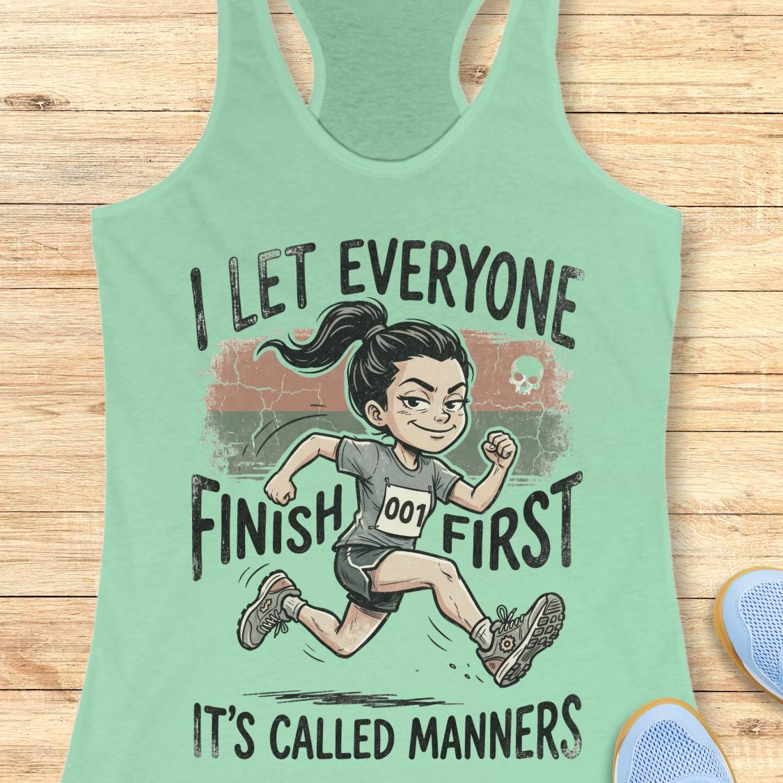 Mint green tank top with a graphic of a runner and text  'I let everyone finish first. It's called manners', on a wooden surface