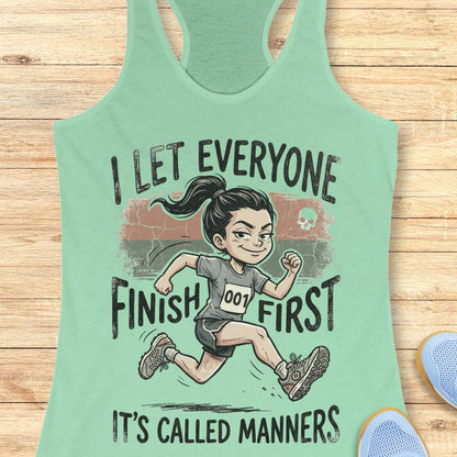 Mint green tank top with a graphic of a runner and text  'I let everyone finish first. It's called manners', on a wooden surface
