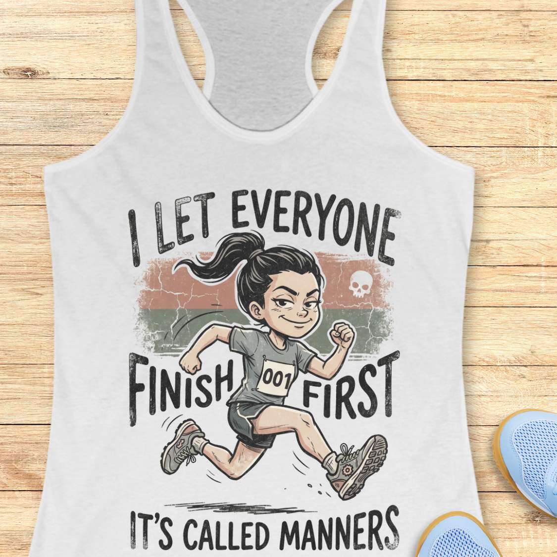 white tank top with a graphic of a runner and text 'I let everyone finish first. It's called manners', on a wooden surface