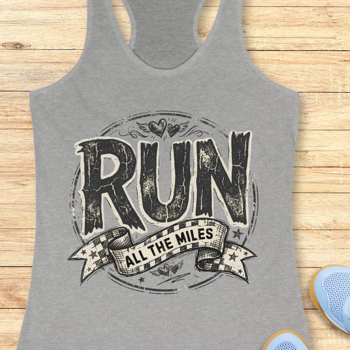 Gray tank top with 'RUN ALL THE MILES' text on a wooden surface