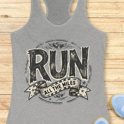 Gray tank top with 'RUN ALL THE MILES' text on a wooden surface