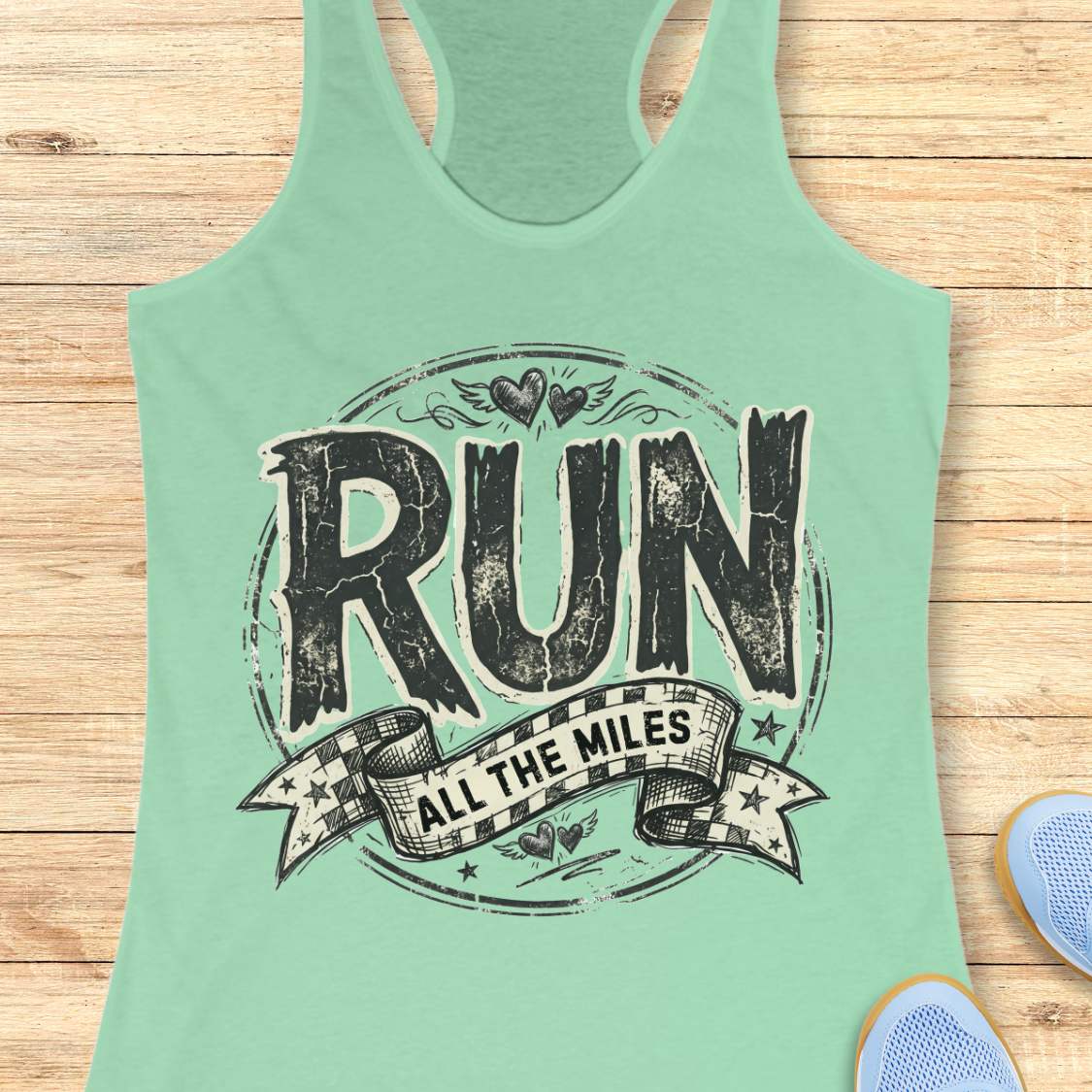 Mint green tank top with 'RUN ALL THE MILES' text on a wooden surface