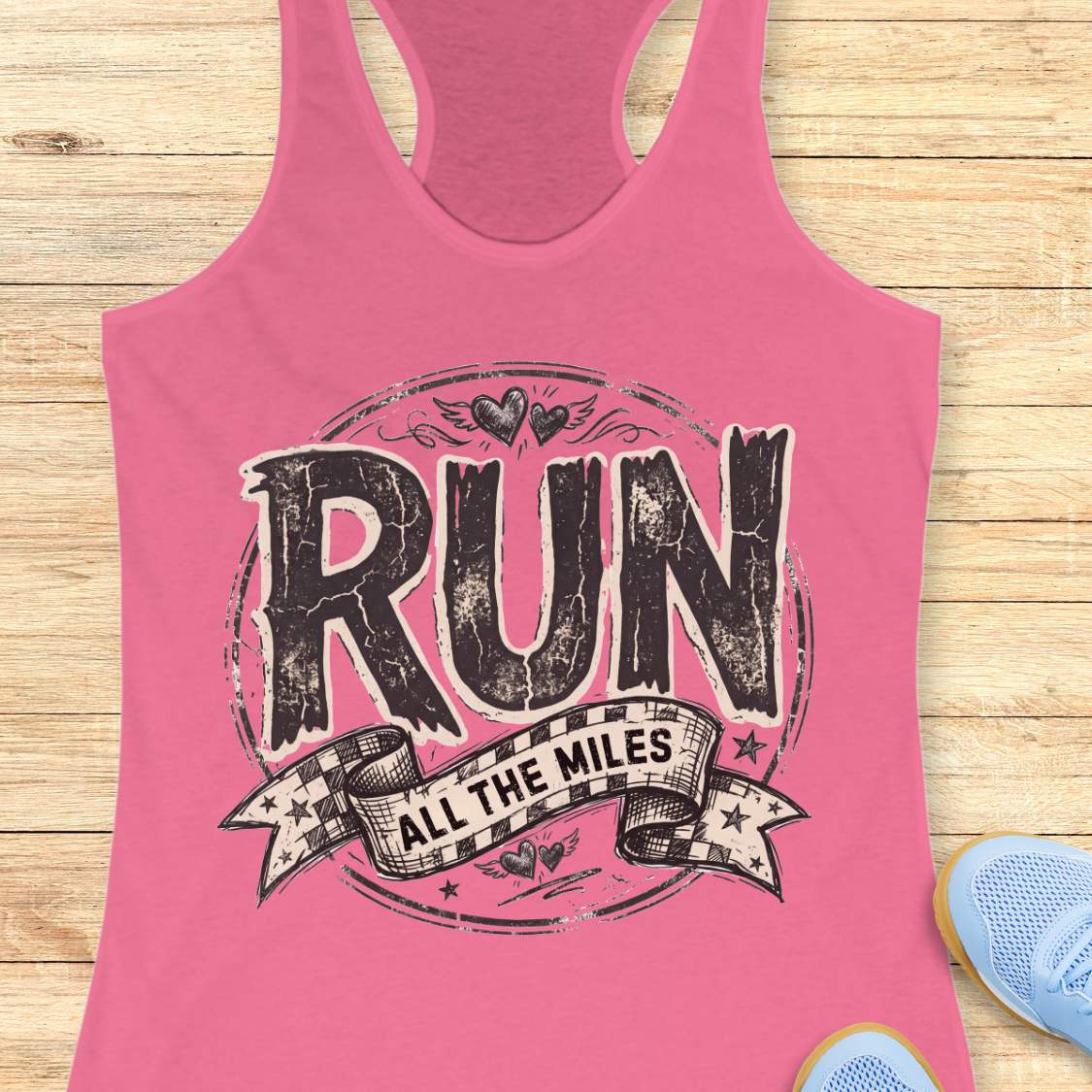 Pink tank top with 'RUN ALL THE MILES' text on a wooden surface